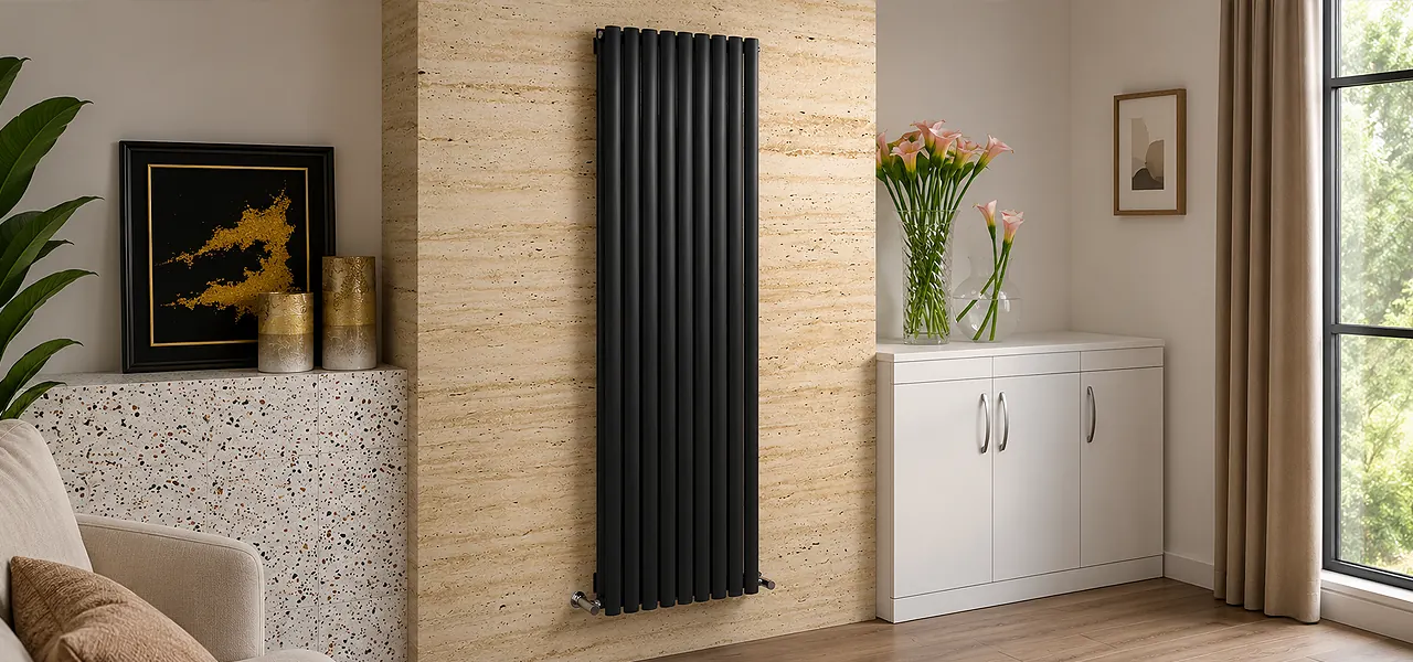 Anthracite vertical designer radiator with rounded oval columns, mounted on a travertine-effect wall beside a vase of flowers.