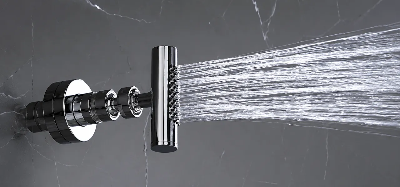 Chrome shower body jet spraying a fan of water across a dark marble-effect wall.
