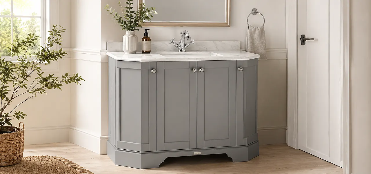 White freestanding double-ended bath with brass floor-standing taps, in front of art deco wallpaper and a fireplace on a dark wood floor.