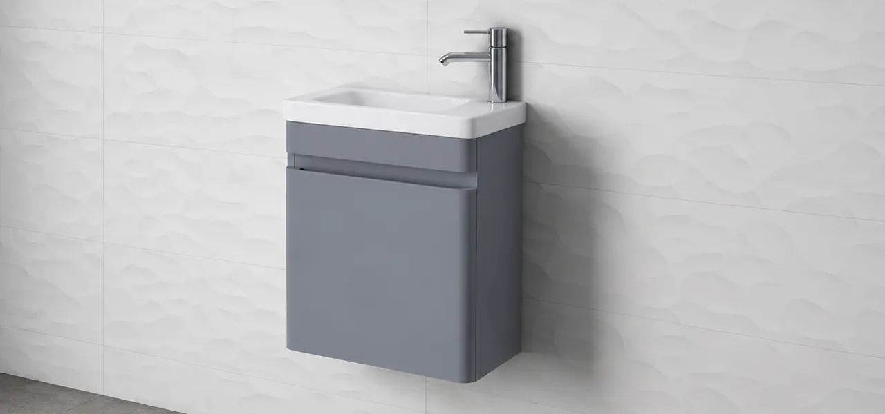 Grey wall-hung cloakroom vanity unit with a slimline basin and side-mounted chrome tap, against textured white wave-pattern tiles.