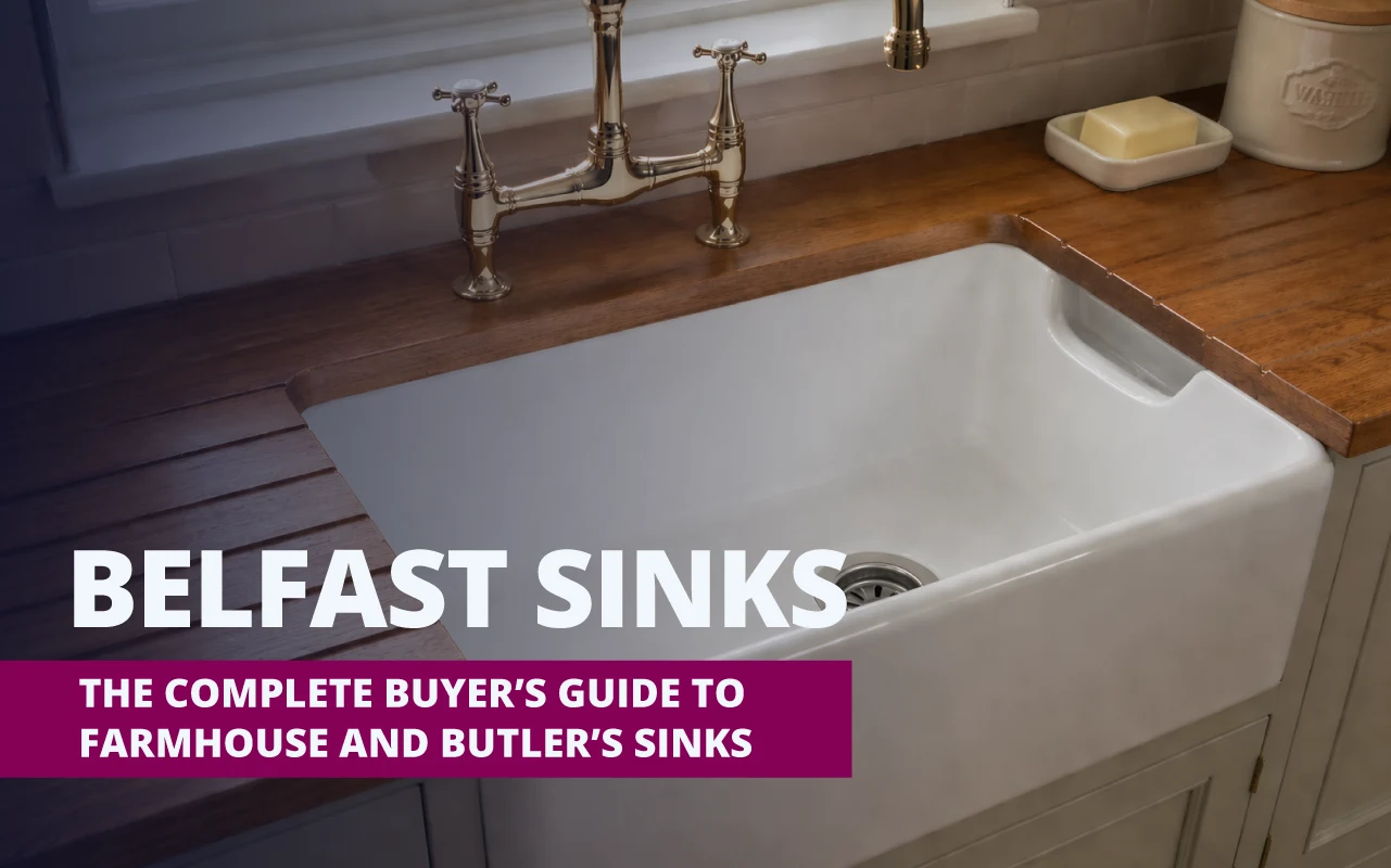 White farmhouse-style Belfast sink set into a dark wooden countertop beneath a polished brass faucet, with overlaid text reading “Belfast Sinks – The Complete Buyer’s Guide to Farmhouse and Butler’s Sinks.”